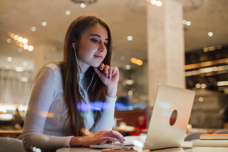Young woman works on laptop in earphones in office